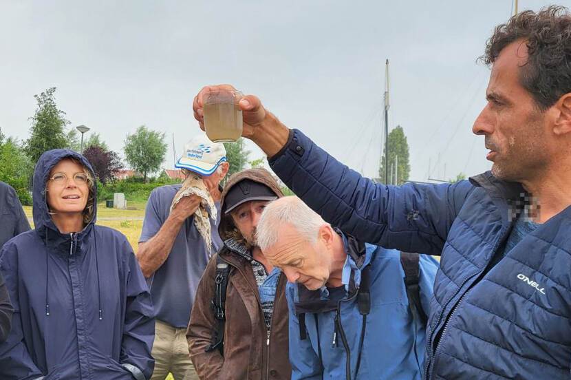 Mensen luisteren naar een spreken die een potje water vasthoudt.