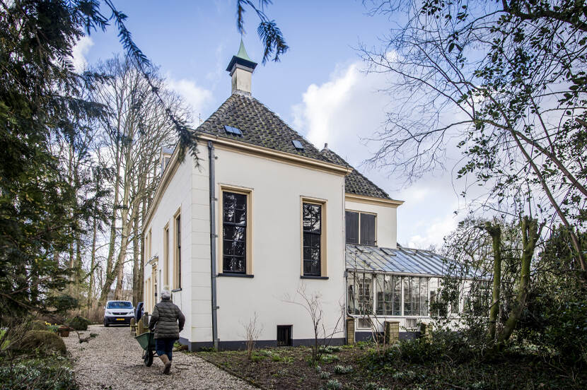 Een wit landhuis in Vreeland, op de voorgrond een persoon met een kruiwagen.